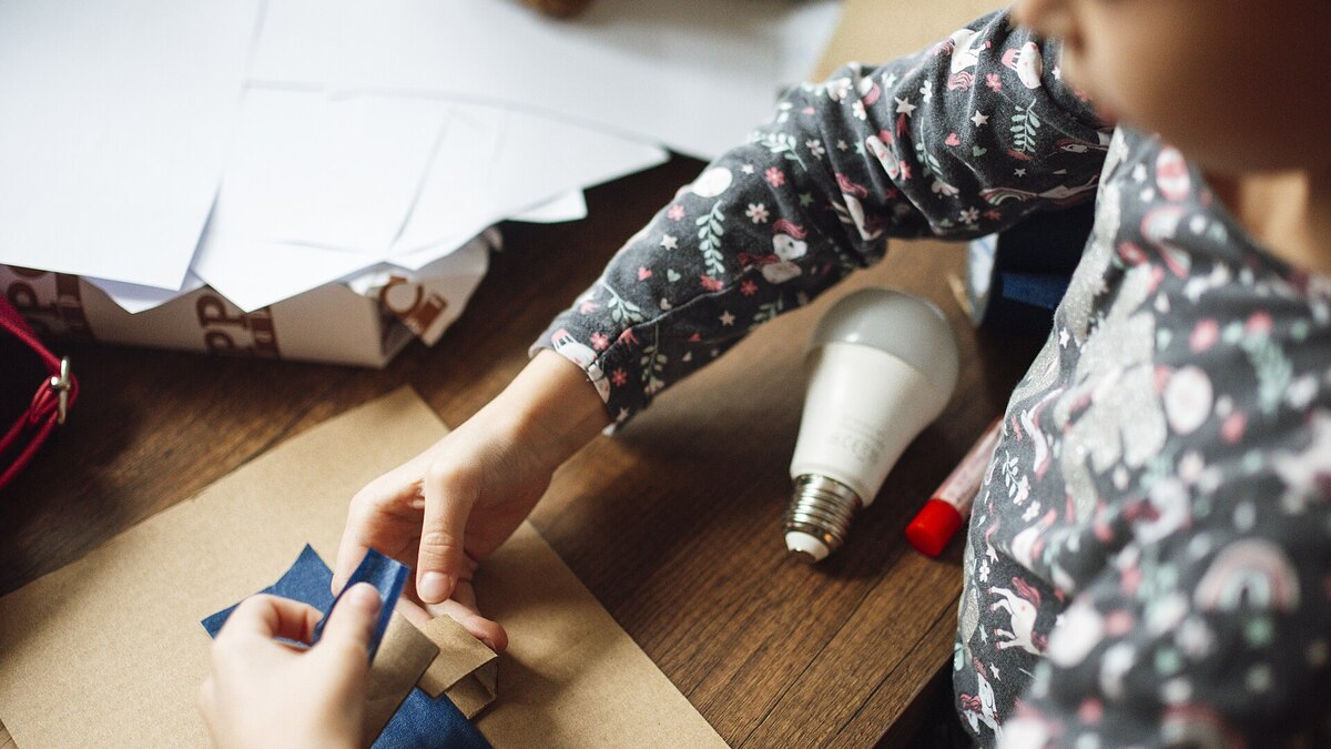 Enfant réalisant une activité créative avec du carton et du matériel de bricolage à la maison
